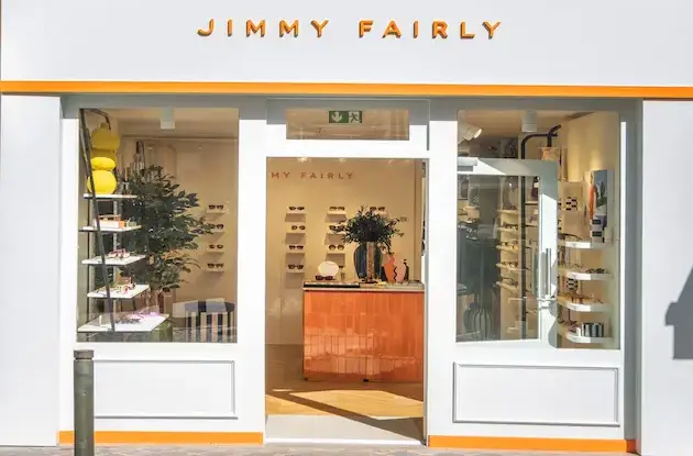 Façade de boutique Jimmy Fairly avec lettres découpées dorées et comptoir orange cuivre visible.