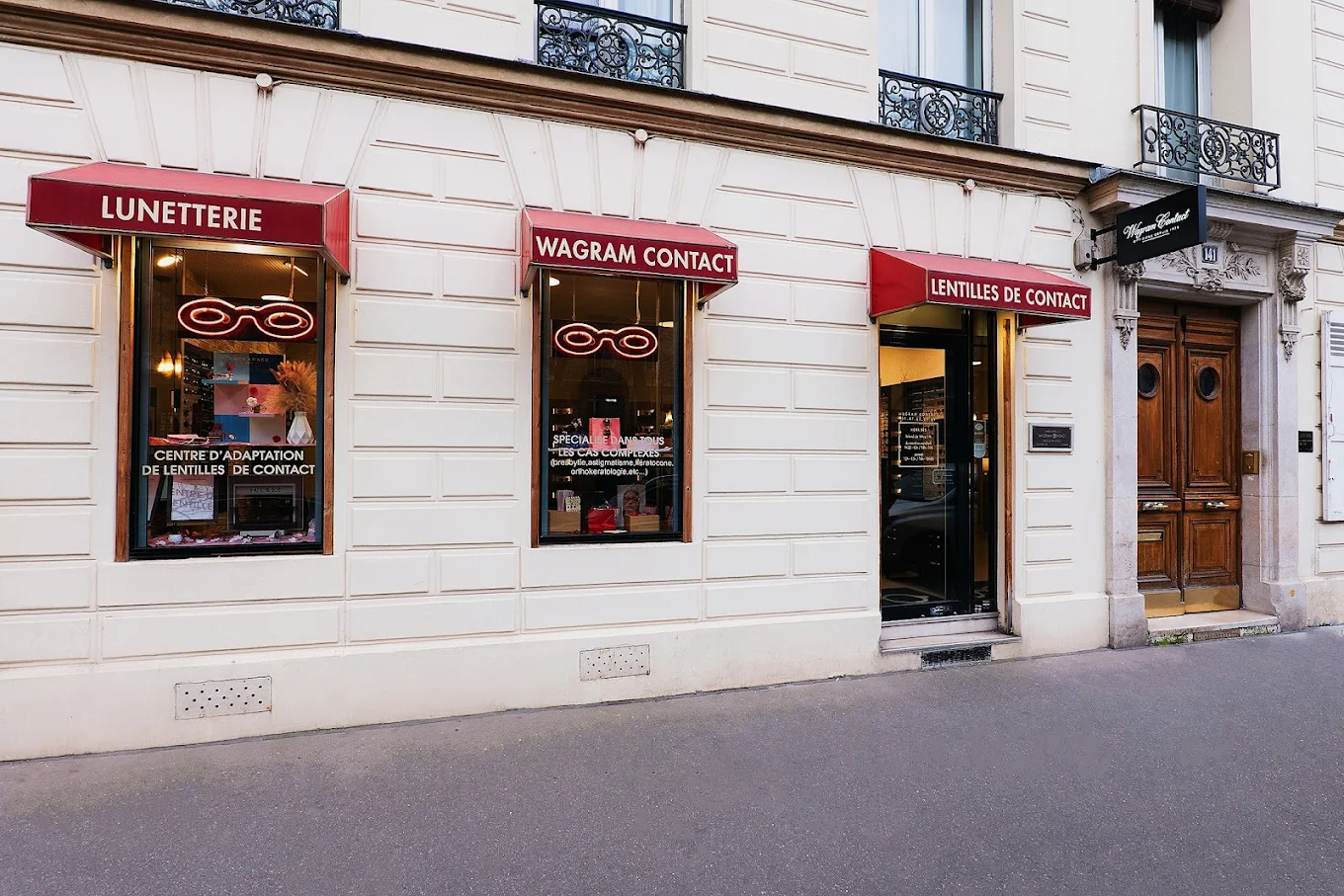 Façade d'optique avec trois stores bannes rouges marqués 