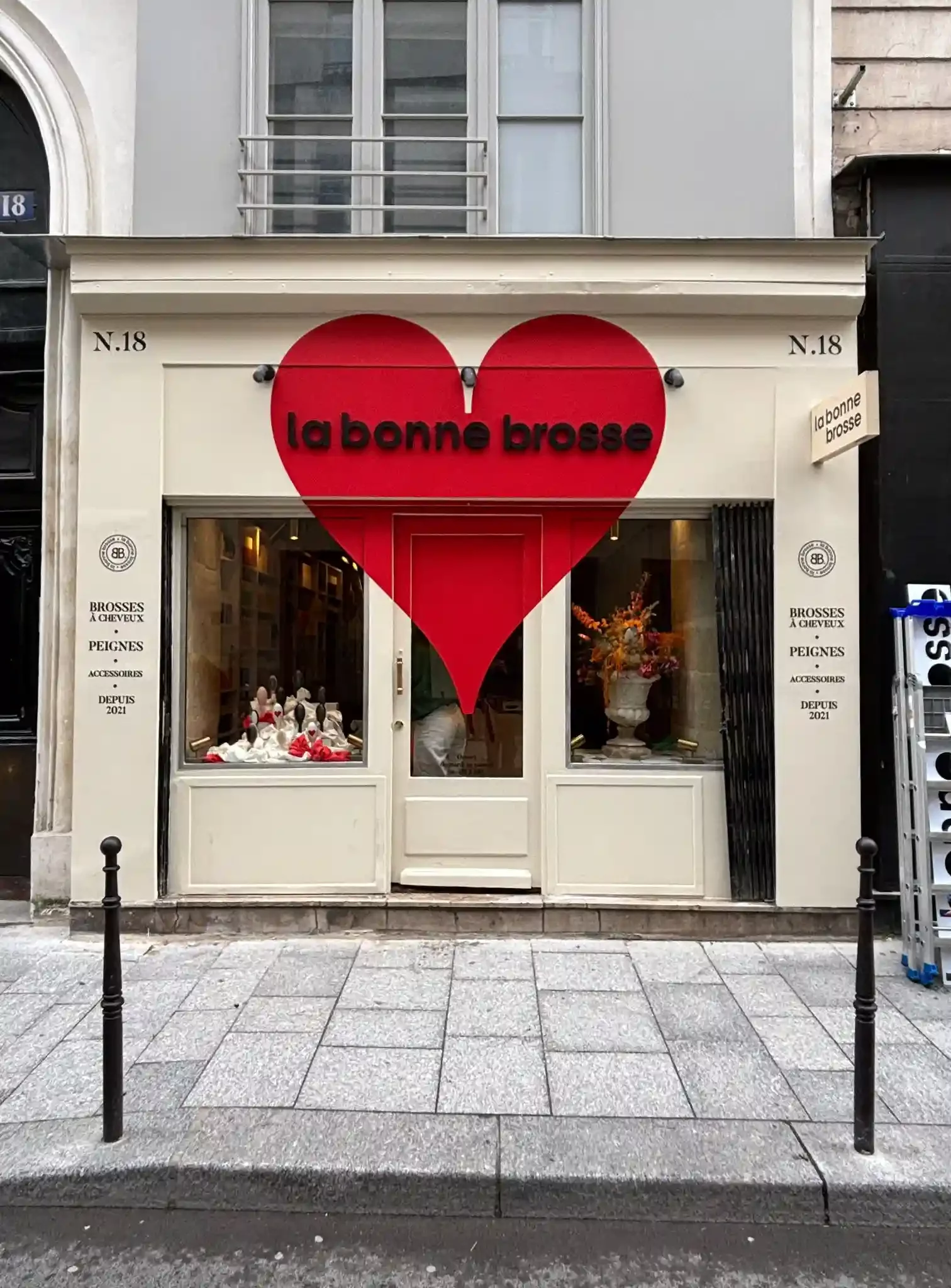 Devanture de la boutique La Bonne Brosse, couleur beige, Grand sticker rouge à la forme d'un coeur qui entoure l'enseigne sous forme de lettres découpées