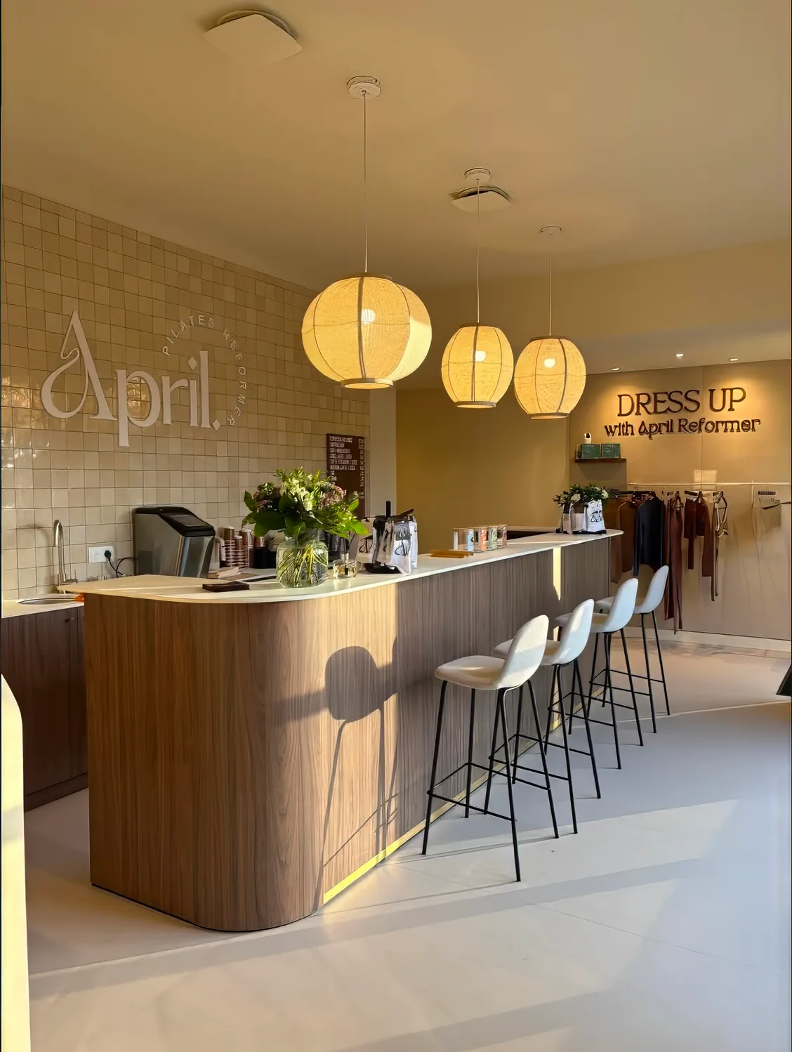 Intérieur élégant de la salle de sport April Reformer avec comptoir en bois, tabourets et enseigne murale 